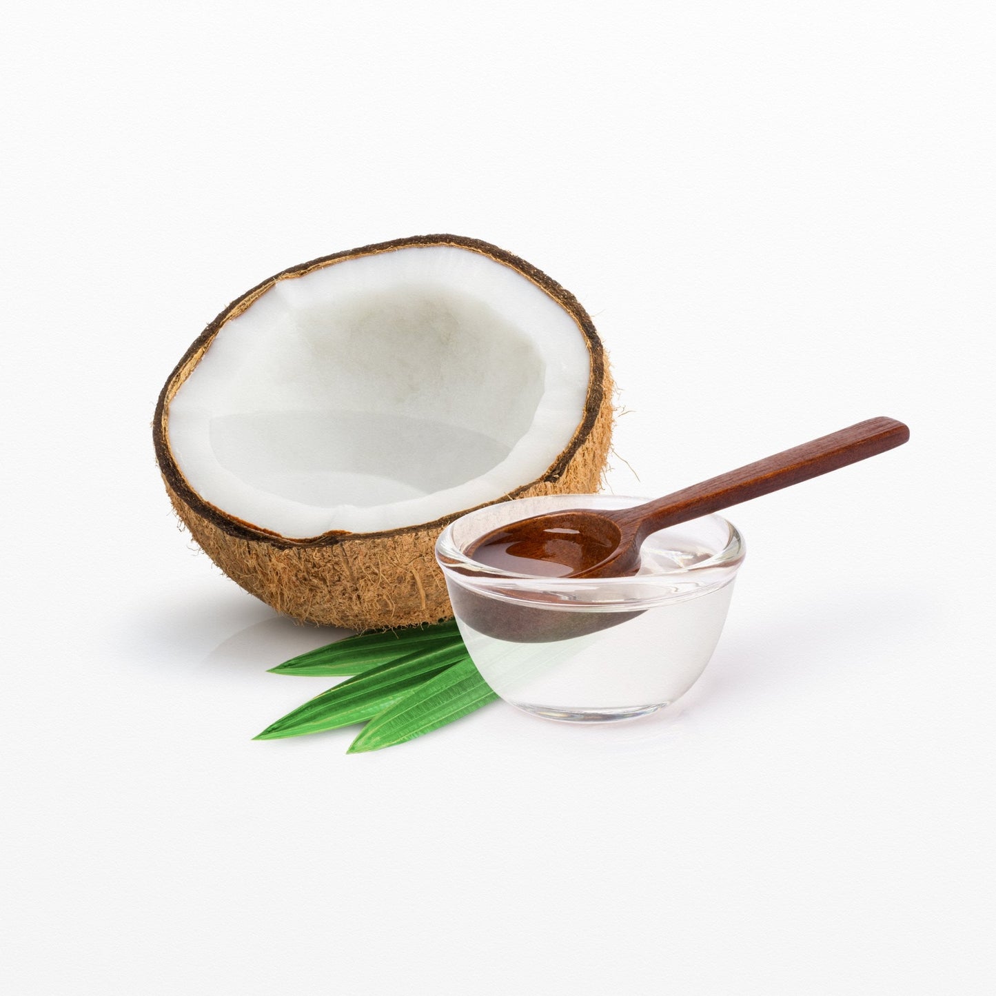 Extra Virgin Coconut Oil with half a coconut, small glass bowl and wooden spoon on green leaves