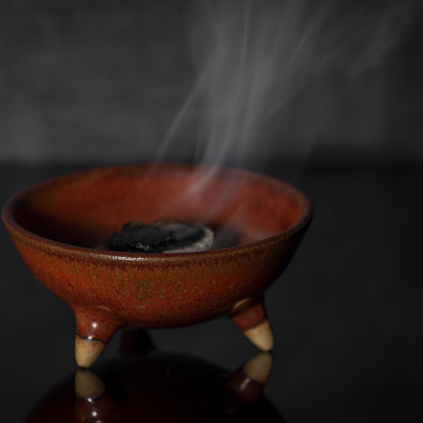 brown ceramic incense bowl with burning charcoal and rising smoke for frankincense incense