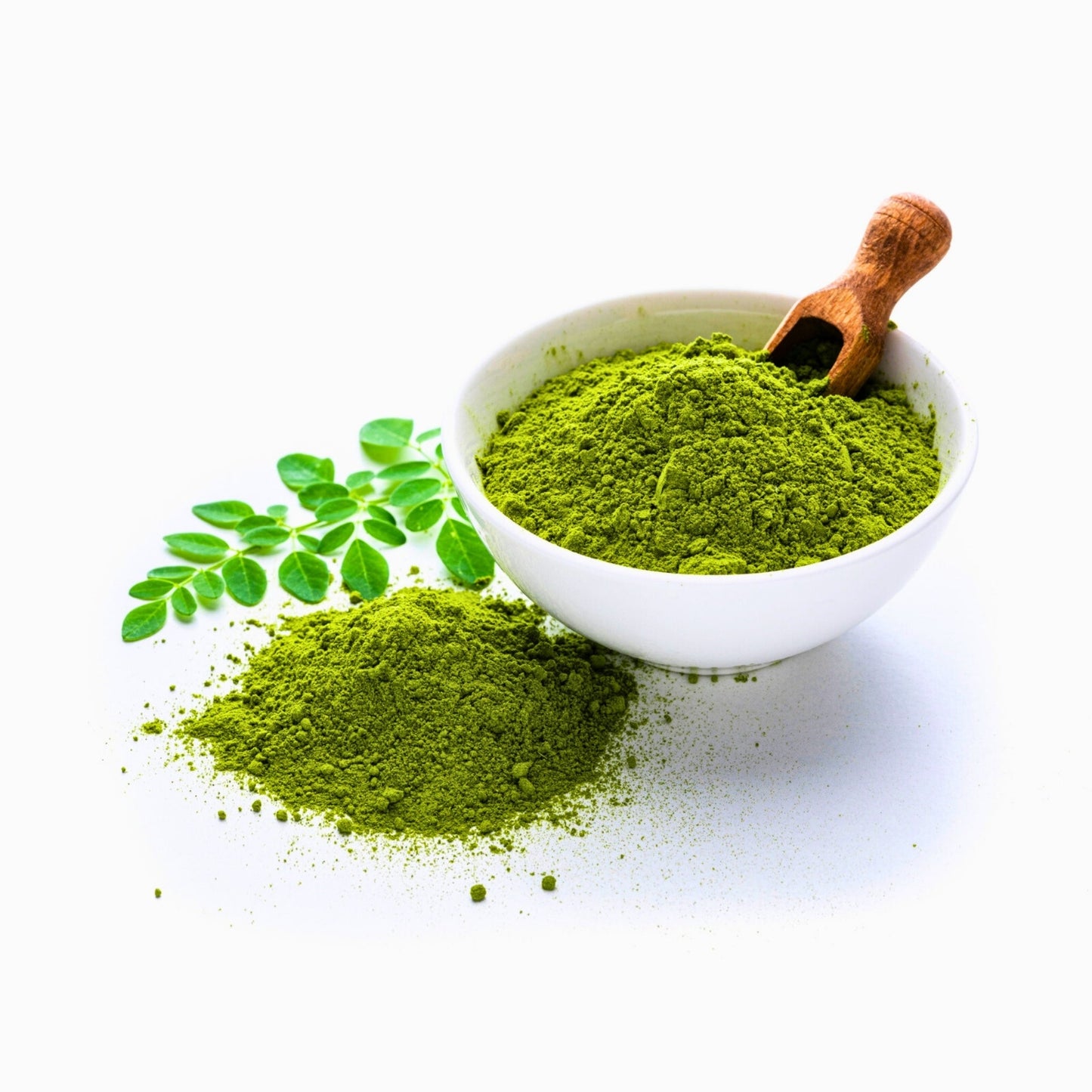 Organic Moringa leaf powder in white bowl with wooden scoop and fresh moringa leaves on white background