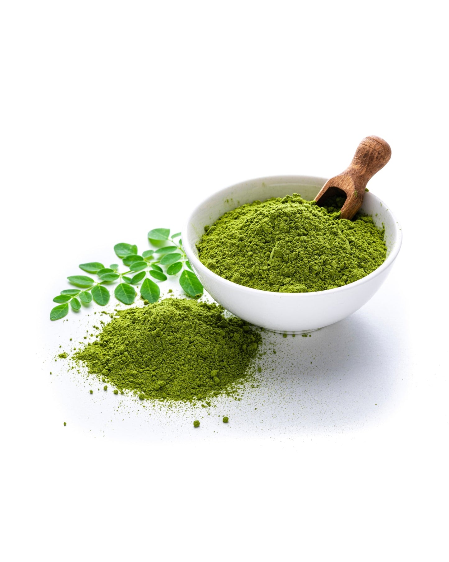 Bowl of vibrant green moringa leaf powder with wooden scoop and fresh moringa leaves on white background