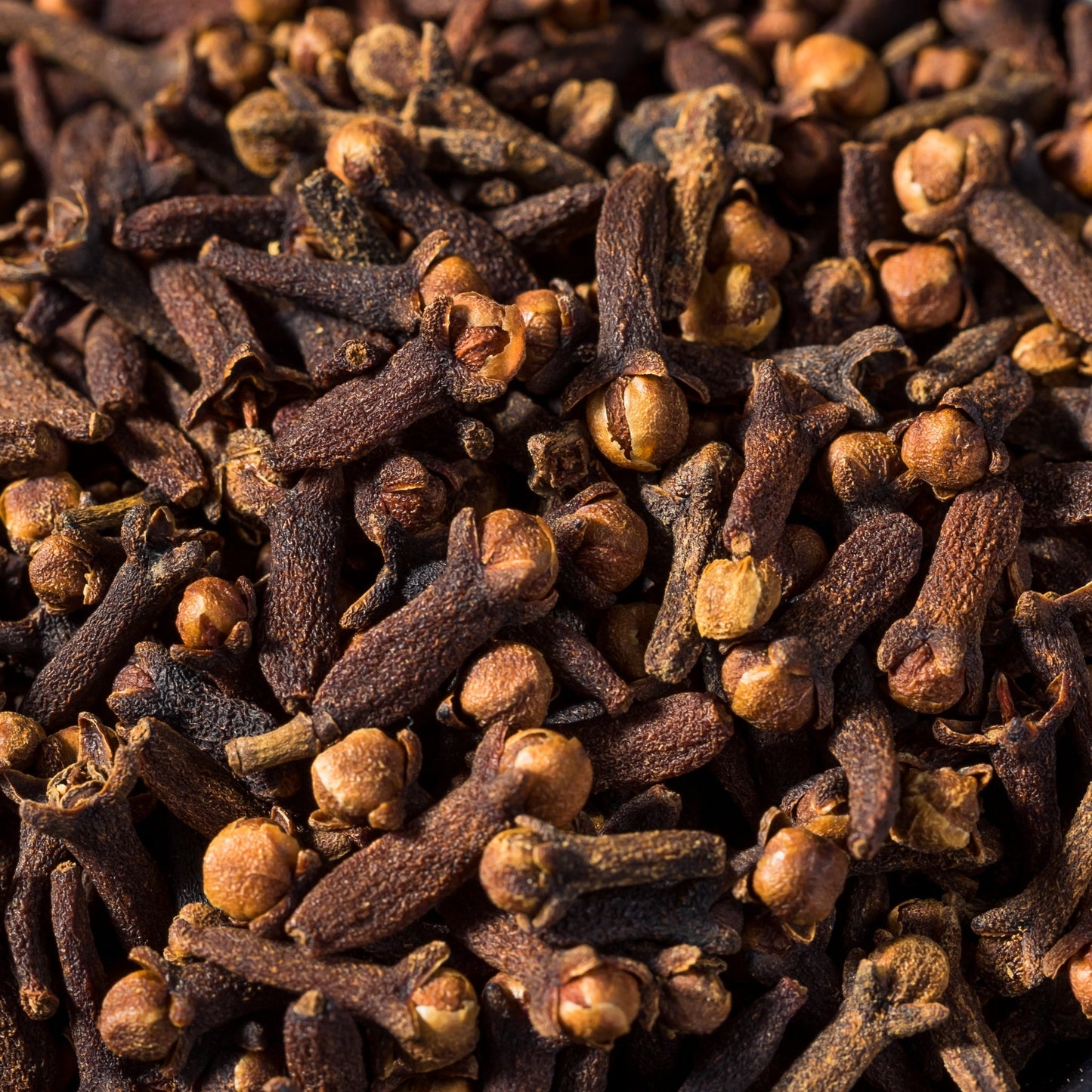 Close-up of dried whole clove buds (Syzygium aromaticum) in 100g quantity, aromatic and spicy for culinary and herbal uses